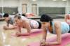 Ein Gruppe auf Yogamatten in einer Turnhalle macht Rumpfübungen