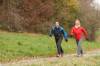 Mann und Frau beim Nordic Walking auf Wanderweg im Herbst