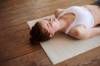 Frau liegt mit geschlossenen Augen auf Yogamatte