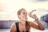 Junge Frau trinkt Wasser aus Flasche nach Sport