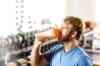 Dunkelblonder Mann mit Vollbart trinkt im Gym aus einem Plastikbecher eine trübe Flüssigkeit