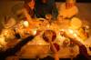 Sechs Personen prosten sich an festlicher Tafel bei Kerzenlicht zu