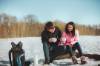 Junges Paar sitzt auf Baumstamm und macht ein Picknick im Schnee