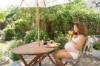 Schwangere Frau trinkt Orangensaft im Garten