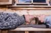 Zwei Frauen liegen auf einer Holzbank auf Filzdecken und sonnen sich Kopf an Kopf