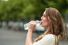 Frau trinkt aus einer Plasteflasche Wasser