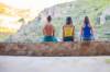 Drei junge Personen sitzen auf einer Steinmauer