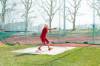 Margaritha Dähler (71) führt in roter Sportbekleidung auf einem Sportplatz in einem Wurfkäfig einen Hammerwurf aus
