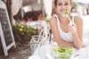Junge Frau sitzt im Restaurant draussen und isst fröhlich einen Salat