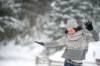 Junge Frau in Strickwaren gewandet und Glitzergürtel an der Jeans tanzt während es schneit